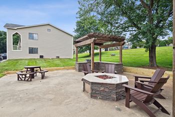 A patio with a fire pit and chairs.